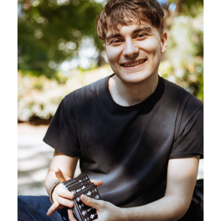 Photo of smiling person with brown hair and tarot deck in their hands