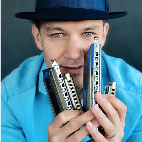 Man in a hat holding harmonicas