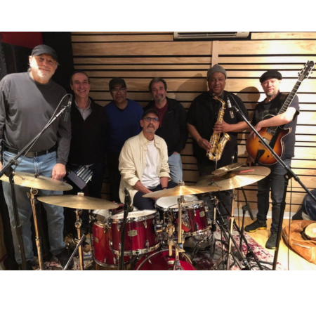 Sextet of musicians behind red drum set