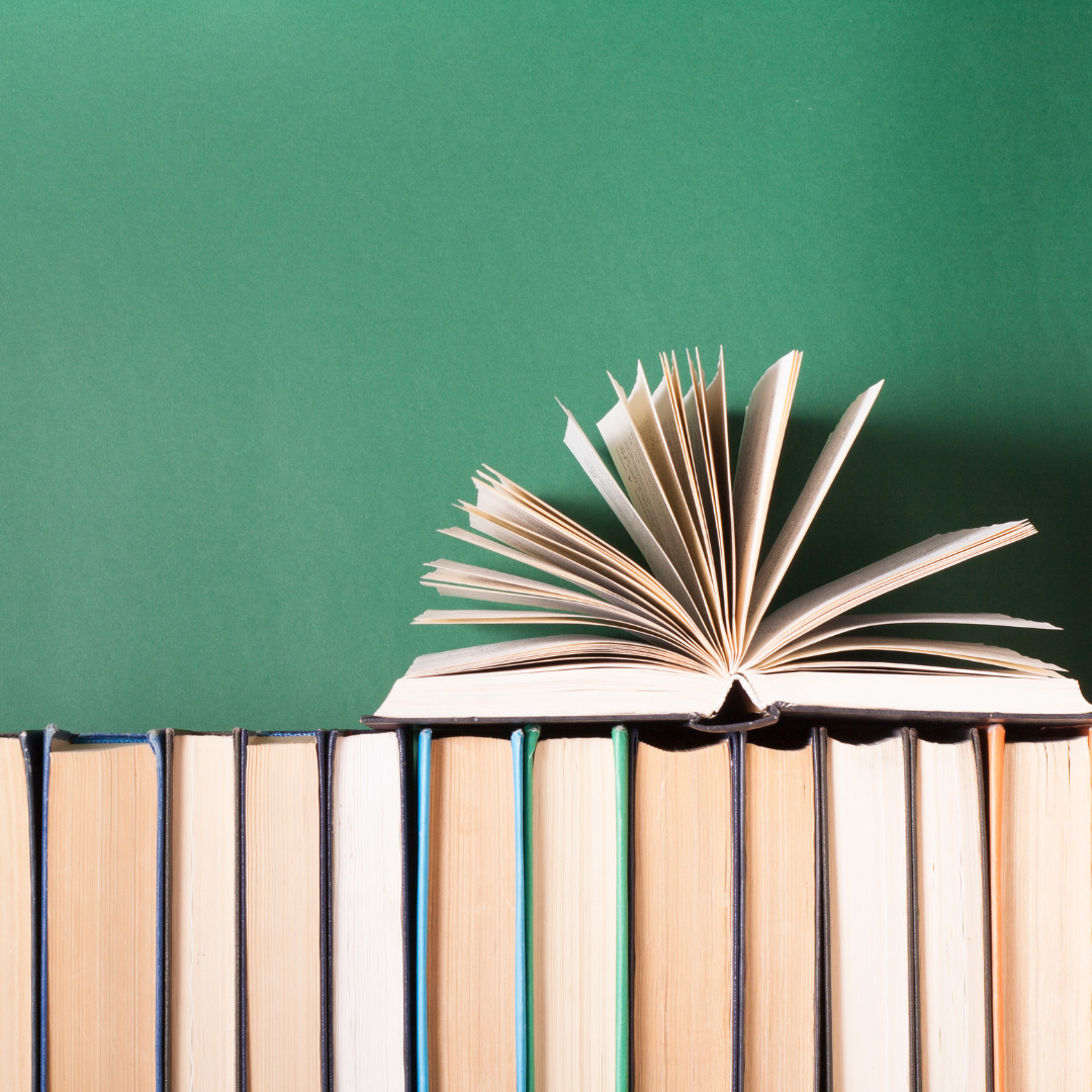 Photo of an open book on top of closed books